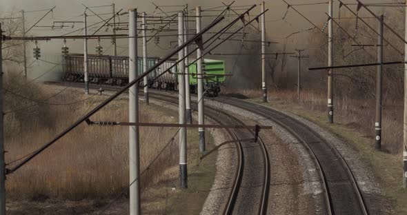 The Freight Train Runs Along The Railway Tracks Between The Burning Fields alt