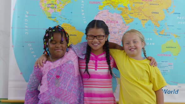 Portrait of three multi-cultural girls in school classroom alt