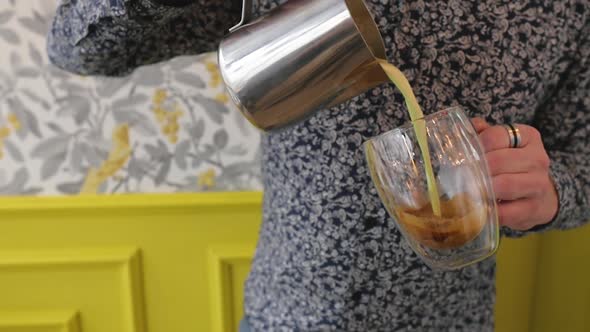 Man Pours Cream Into Coffee Close-up on the Background of the Cafe. Baristo Pours Coffee Kien in a alt