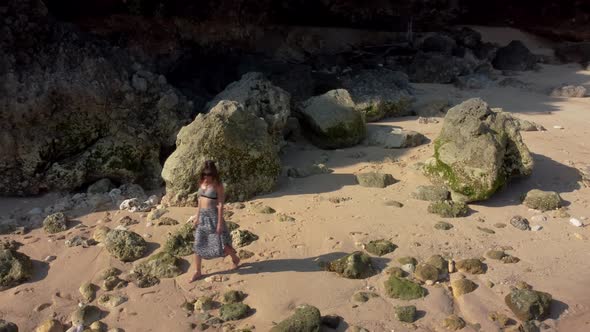 Woman Walks in the Beach Near to Rocks Seaweed alt
