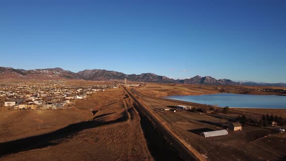 Railway leading from Denver to the foothills of Boulder Colorado during golden hour, aerial alt