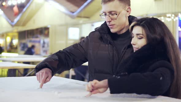 Young Couple Paints Using Their Fingers on the Snow alt