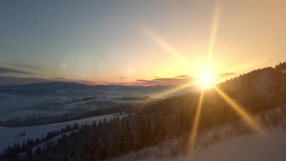 Flight Over Carpathian Mountains in Winter at Sunrise. Aerial View of a Snow-covered Mountain. Rural alt