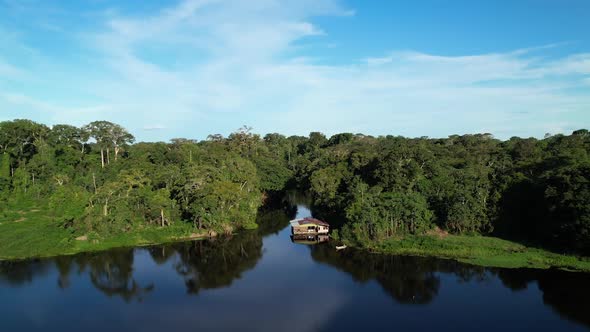 Cinematic shot of the Mighty Amazon river surrounded by tropical jungle green rainforest and a small alt