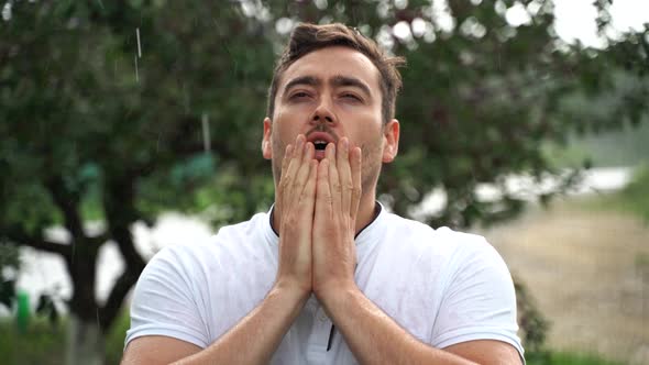 Portrait of a Young Man Looking at Camera As He Covers His Face with His Hands alt