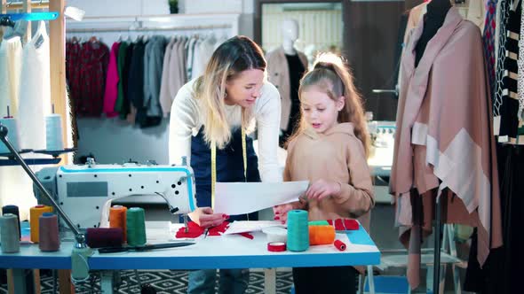 A Girl and a Seamstress are Observing a Drawing alt