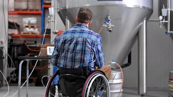 Man in Wheel Chair Working in Brewery Factory alt