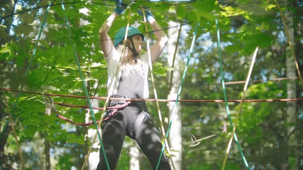 Blonde Woman Walking on the Rope - an Entertainment Attraction in the Green Forest alt