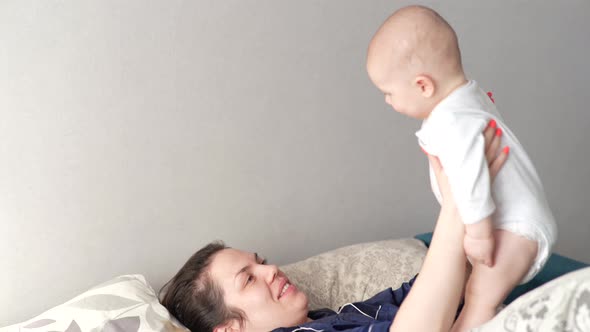 Mother Plays with Her Baby at Home on Her Lap