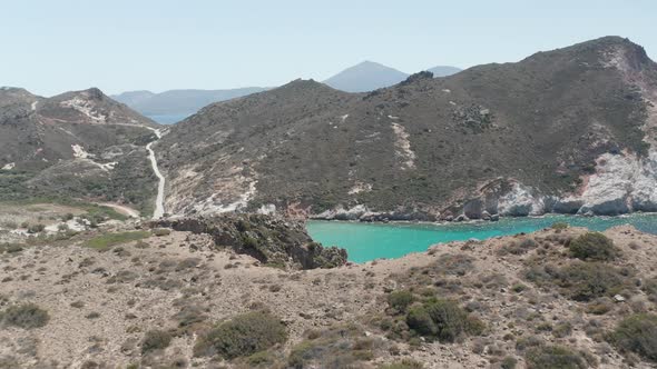 Aerial Flight Over Dry Island in SUmmer Heat Revealing Turquoise Blue Ocean with Rocky Cliff Coast alt