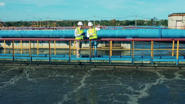 Two Wastewater Treatment Operators Inspecting a Clarifier alt