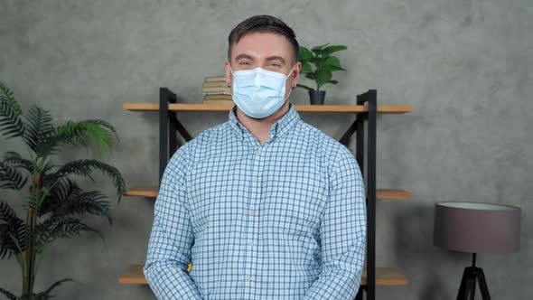 Smiling businessman in protective medical mask on face turns head looking camera alt