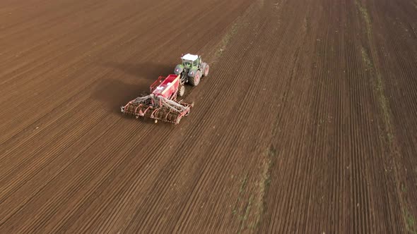 Tractor in Working in the Field. Tractor with a Modern Sowing Seeds Machine in a Newly Plowed Field alt