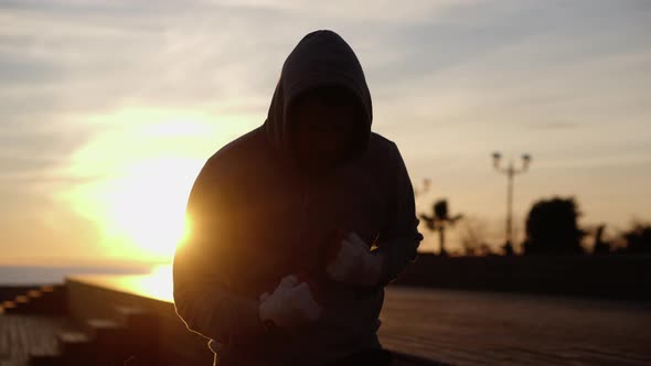 Sportsman Is Training a Running in Place in Sunset Time on Embankment alt