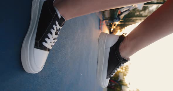 Female Legs Sitting on a Basketball Court in Black Gumshoes Vertical Video alt