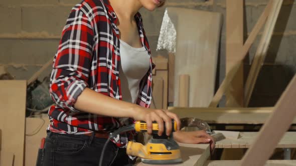 Female Carpenter Sanding Wood at Her Workshop alt
