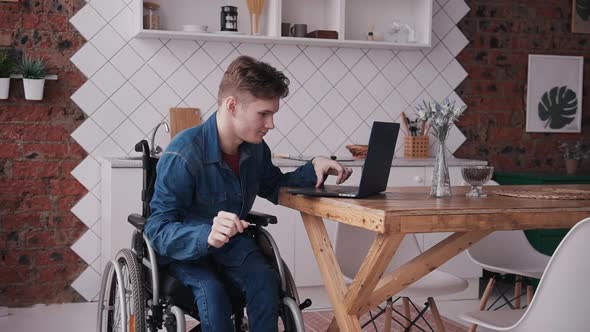 Man in Wheelchair Working with Laptop at Home