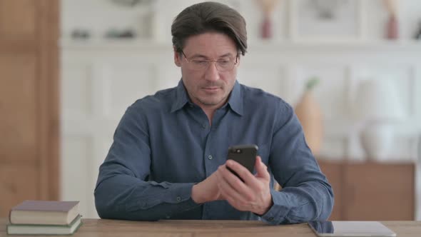 Attractive Young Man using Smartphone in Office alt