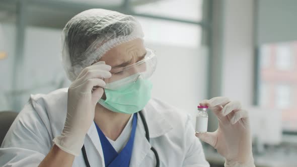 A Bottle of Medicine in the Hands of an Experienced Doctor in the Medical Office of a Private Clinic alt