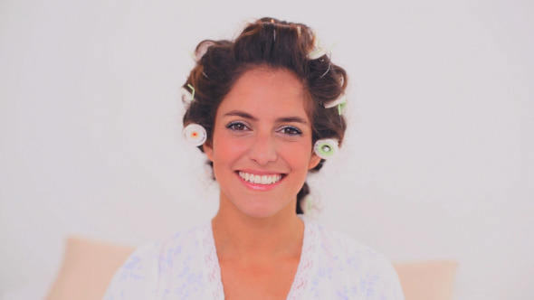 Smiling Woman In Hair Curlers Brushing Her Eyebrow