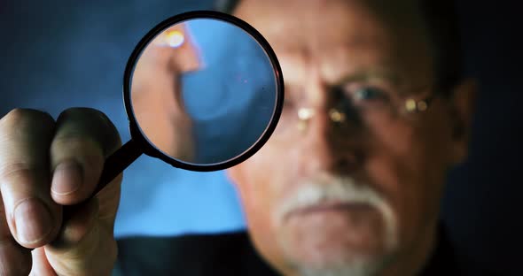 Enlarged Eye Of Mature Tax Inspector Looking Through Magnifying Glass