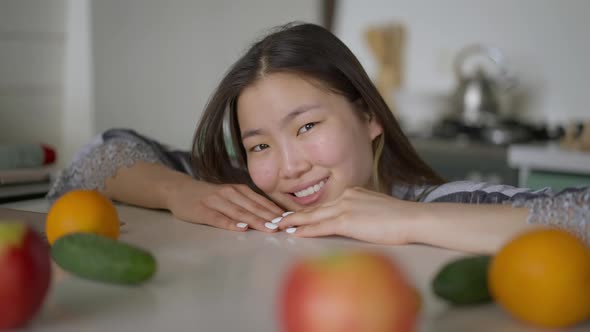 Closeup Portrait of Smiling Charming Asian Woman Posing in Kitchen Indoors alt