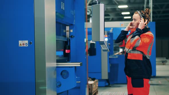 Woman with Headphones on Operates a Machine Via Touchscreen alt