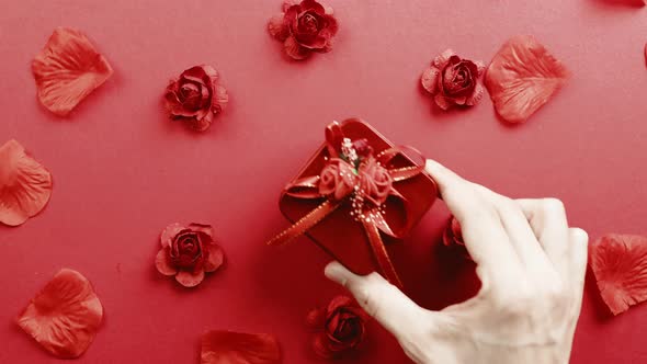 Red Gift with Petals Falling Down on the Background alt