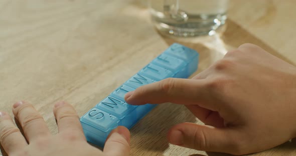 Man's Hands Taking Pills From Plastic Pill Organizer Box