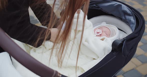 Mom Puts A Newborn Baby Girl In A Stroller On A Walk