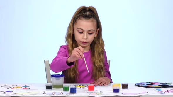 Kid Paints a Picture, Wets a Brush in a Glass with Water. Close-up. White Background alt