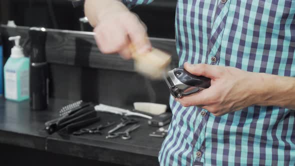 Unrecognizable Barber Cleaning His Electric Clipper After Working alt