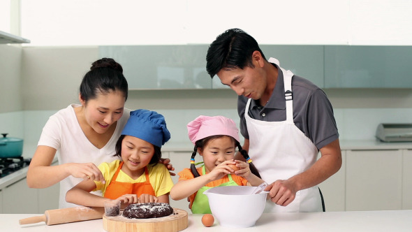 Smiling Parents And Cute Daughters Baking Together