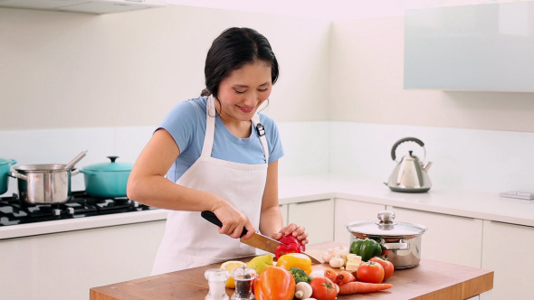 Smiling Woman Slicing Vegetables With Large Knife