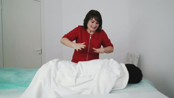 Playful Therapist in Uniform Massages Lady Through Bathrobe alt