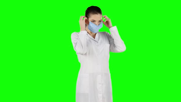 Female Nurse Puts on a Blue Medical Mask, Green Screen alt