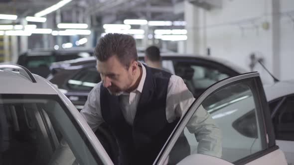 Portrait of Confident Caucasian Businessman Opening Car Door and Touching Automobile. Wealthy Man alt
