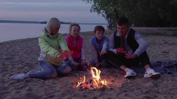 Father, Mother and Children Warming By Fire During Evening Halt By Sea