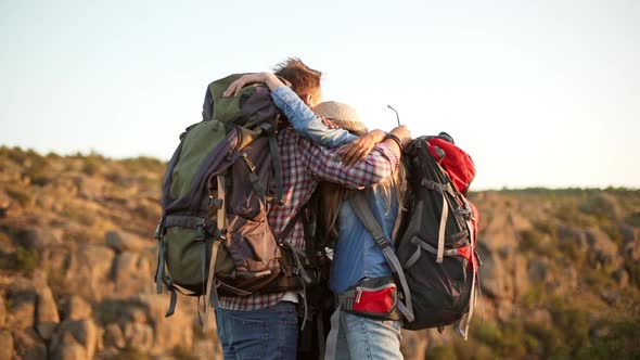 Three Happy Tourists Friends Hugs Each Other Admiring View Smiling Wearing Backpacks and Film Camera alt