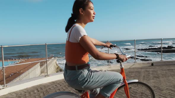 Side view of a mixed race girl riding a bike seaside alt
