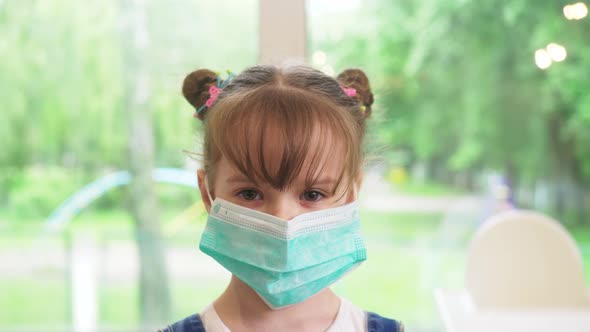little girl wearing a medical mask closeup looking at camera - Concept of coronavirus protection.