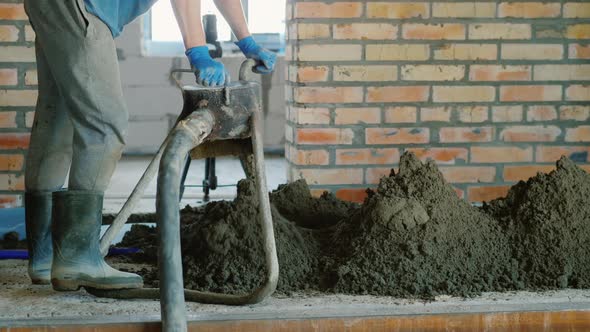 The Builder Puts a Semi-dry Mortar for Finishing the Floor alt