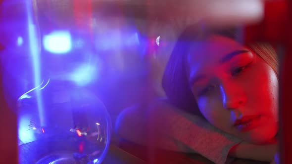 4K Portrait of Loneliness Asian woman sitting in nightclub with illuminated neon night lights alt