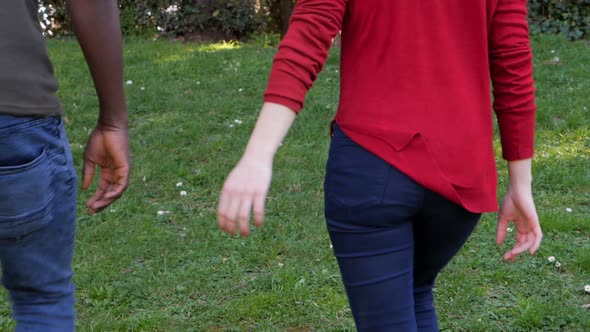 Young interracial lovers holding hands in the park.Mixed race love concept alt