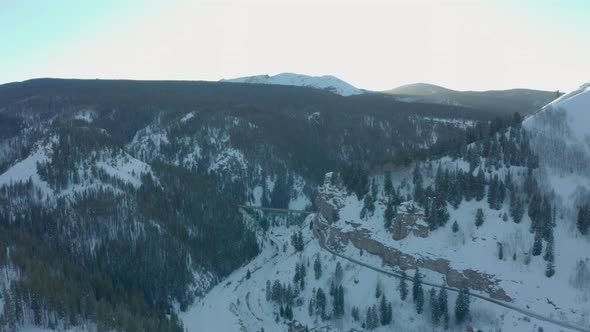 Aerial Drone Shot Flying Over Snowy Colorado Valley Toward Scenic Green Bridge