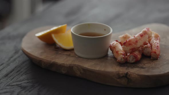 Slow Motion Gimbal Shot of Crab Leg Meat on a Olive Board with Sweet Lemon and Dip Sauce alt