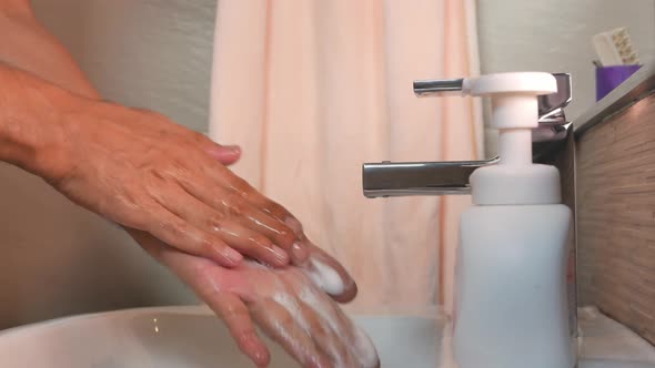 Washing hands with tap water from the sink and cleaning foam.