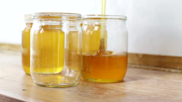 Bee Honey is Poured Into Jars on a Sunny Day Background alt