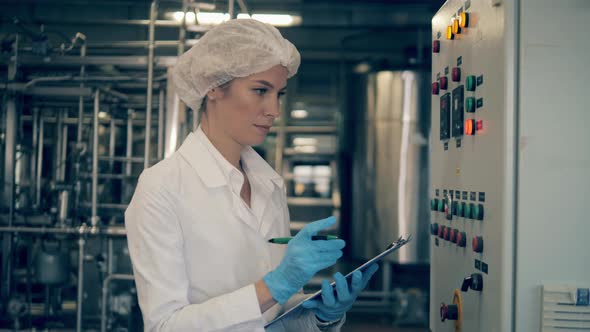 Woman, Female Factory Engineer Works with Factory Machine, Checking It. alt