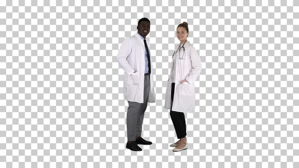 Two caucasian and afro american smiling doctors standing alt